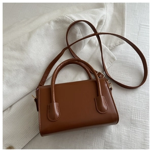 Detail view of brown square tote bag with round handles on white corduroy fabric