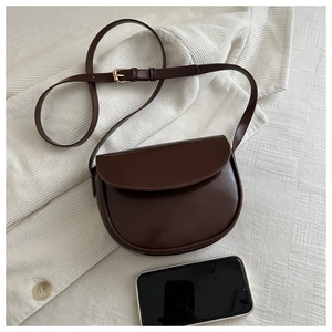 Detailed view of dark brown saddle bag with smooth leather finish and gold hardware