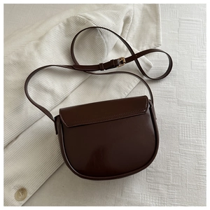 Detail of dark brown PU leather saddle bag with gold hardware and fine stitching