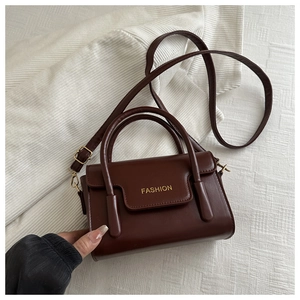 Detail of burgundy vintage square crossbody bag with gold FASHION text on soft fabric