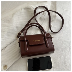 Top-down shot of a vintage brown crossbody bag with gold text on white corduroy texture