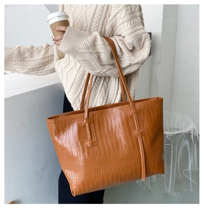 Caramel crocodile pattern tote bag shown over-the-shoulder with stylish fringe detail