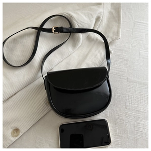 Glossy black saddle bag shown with smartphone for size scale on white background