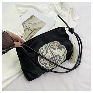 Dettaglio di elegante ricamo cinese e nappa di giada su una borsa di velluto nero