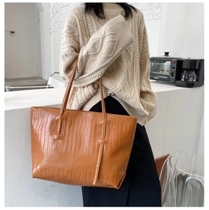 Brown crocodile texture tote bag with slim handles shown in a lifestyle cafe setting