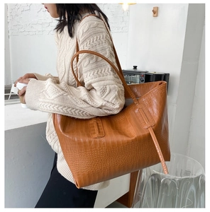 Macro detail of brown crocodile embossed texture on a large stylish tote shoulder bag