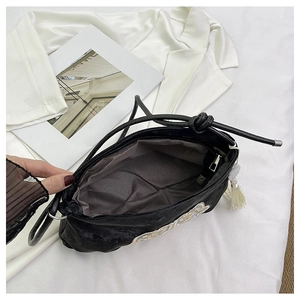 Vista interna di una borsa in camoscio nero con ricami eleganti e nappe bianche