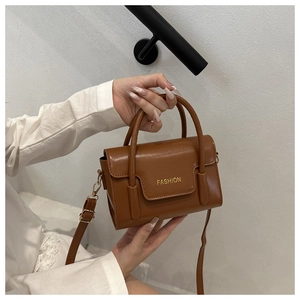 Detail of a brown vintage leather handbag with golden hardware and fashion lettering