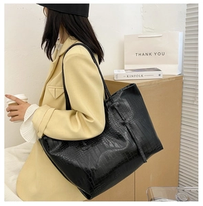 Close-up of black crocodile embossed tote bag with slim shoulder strap for daily use