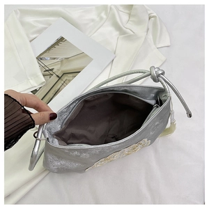 Dettaglio borsa in raso argento con ricamo e tracolla con nodo dal design elegante