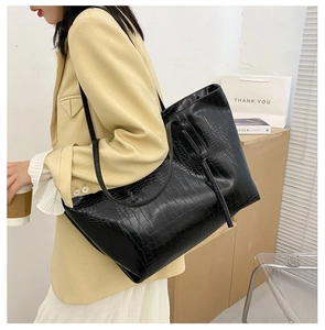 Close-up of black crocodile pattern tote bag showing glossy texture and shoulder straps