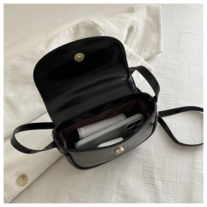 Detail view of the black crossbody bag showing its interior capacity with a phone and wallet