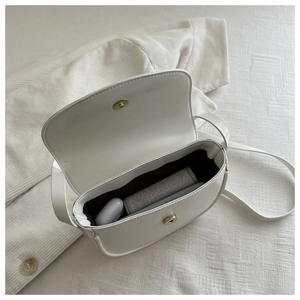 Detail view of white saddle bag interior showing magnetic buckle and brown lining