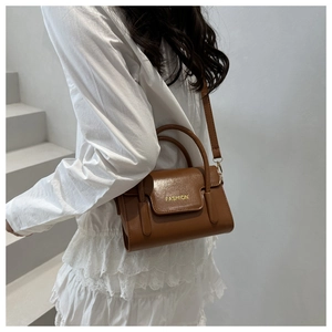 Close-up of a brown leather crossbody bag with a gold Fashion logo on the flap