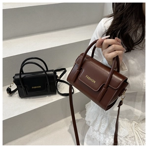 Detail of compact leather handbags with top handles and fashion lettering in black and brown