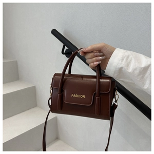 Detailed close-up of dark brown retro shoulder bag with gold FASHION lettering