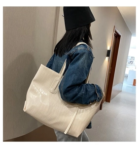 Detailed view of cream crocodile pattern tote bag shown with model in modern interior