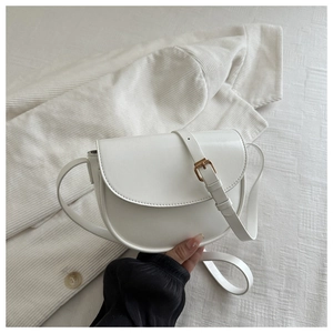 Close-up of minimalist white saddle bag with adjustable strap on textured fabric