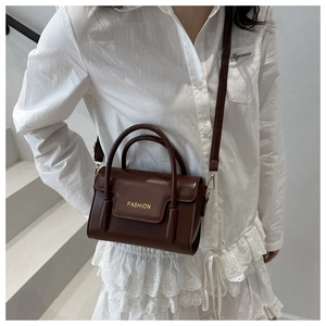 Brown leather crossbody bag with top handles and fashion text shown on a female model