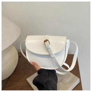 Detailed view of a white semi-circular saddle bag with gold buckle and adjustable strap