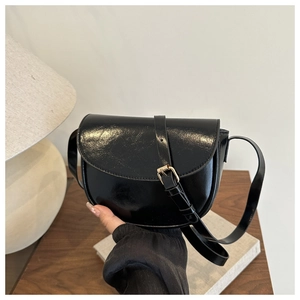 Detail of a black semi-circular saddle bag with glossy finish and gold adjustable buckle