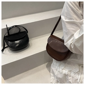 Detail view of retro saddle shoulder bags in black and brown finishes for women