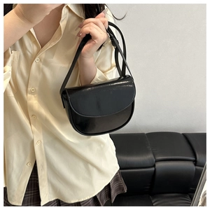 Detail view of glossy black semi-circle saddle bag styled with a minimalist outfit
