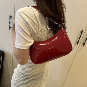 Glossy red patent leather baguette bag with gold chain strap for shoulder and crossbody wear