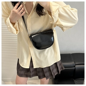 Classic black patent leather saddle bag with shoulder strap shown on a female model