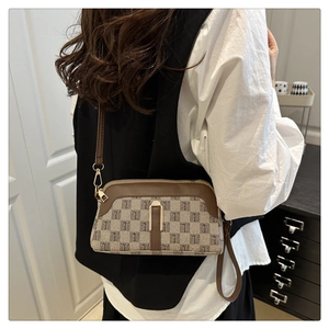 Détail du sac à bandoulière en tissu beige avec garniture en cuir marron et fermoir métal