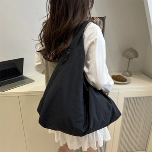 Large black crescent nylon tote bag shown on model back for daily minimalist commute fashion