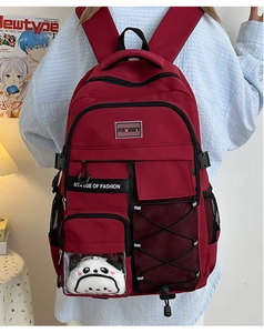 Détail du sac à dos bordeaux pour étudiant avec marque de mode et pendentif panda