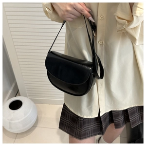 Detail of a vintage black saddle bag with smooth glossy finish and minimalist shoulder strap