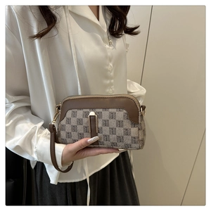 Détail d'un mini sac coquillage en toile avec garniture en cuir marron et zip doré