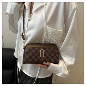 Détail d'un sac bandoulière marron à monogramme avec fermoir en U métallique et sangle en cuir