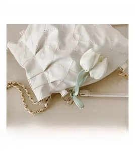 Detail shot of white quilted leather bag with tulip charm and gold chain strap