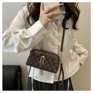Sac à bandoulière marron à damier avec motif T porté avec une tenue minimaliste