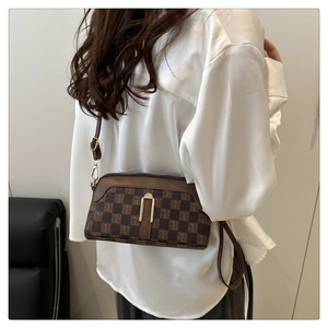 Détail d'un sac bandoulière en toile à carreaux marron avec boucle en U dorée et cuir
