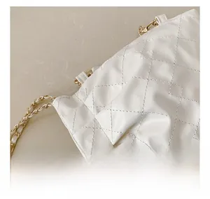 Close-up of white quilted leather texture and gold metal chain strap of this handbag