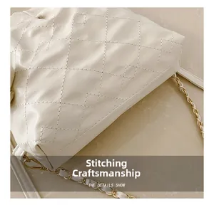 Close-up of white quilted leather bag with stitching craft and gold chain strap