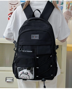 Détail d'un sac à dos ergonomique noir montrant des poches multiples et un pendentif panda