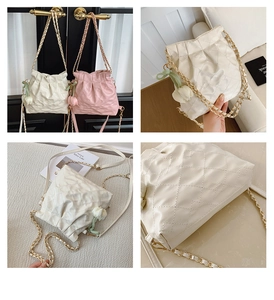 Detail of quilted bucket bag with drawstring closure and tulip charm in white and pink