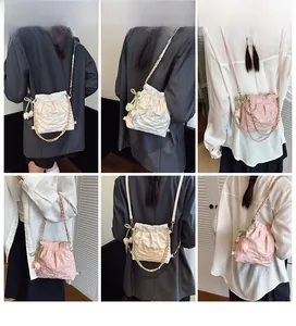 Detail of quilted drawstring bag with gold chain strap and tulip charm in cream and pink
