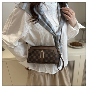 Détail du sac bandoulière vintage aux finitions dorées porté avec une tenue élégante