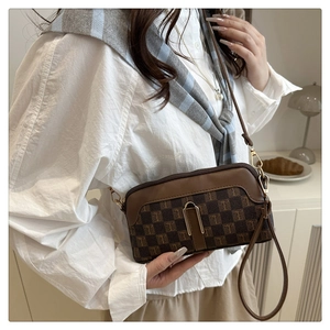 Détail d'un petit sac bandoulière vintage en cuir PU avec motif monogramme et boucle dorée