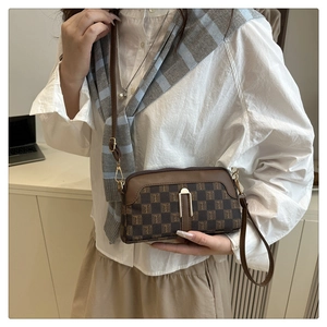 Détail d'un sac bandoulière marron à carreaux avec fermoir métallique sur un modèle