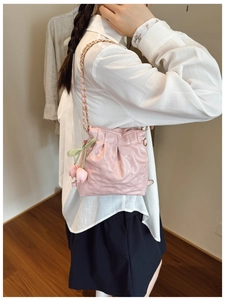 Close-up of pink quilted mini bucket bag featuring cute tulip charms and chain strap