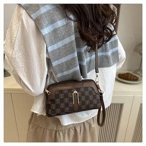 Détail d'un sac bandoulière marron texturé avec motif monogramme et fermoir métallique