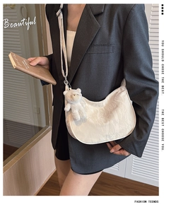 Detail of white dumpling crossbody bag with textured pleats and cute plush bear charm