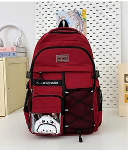 Détail d'un sac à dos rouge multi-poches avec peluche panda et cordon élastique